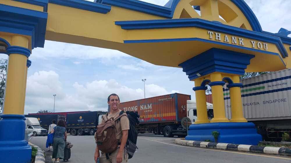 Traveler walking along the road between Malaysian and Thai immigration checkpoints at Padang Besar border crossing.